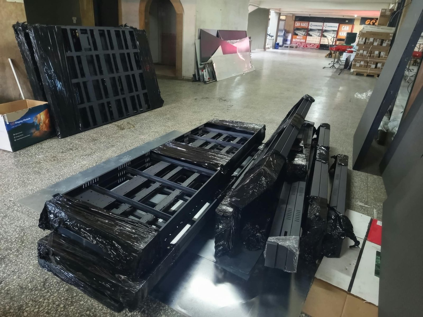 Atölyede bir araya getirilen metal ekran kasaları ve taşıyıcı parçaların görünümü.